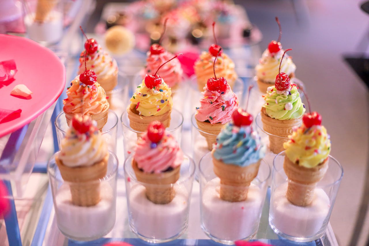 Vibrant ice cream cones with cherries and sprinkles in glass cups, perfect for a sweet treat.