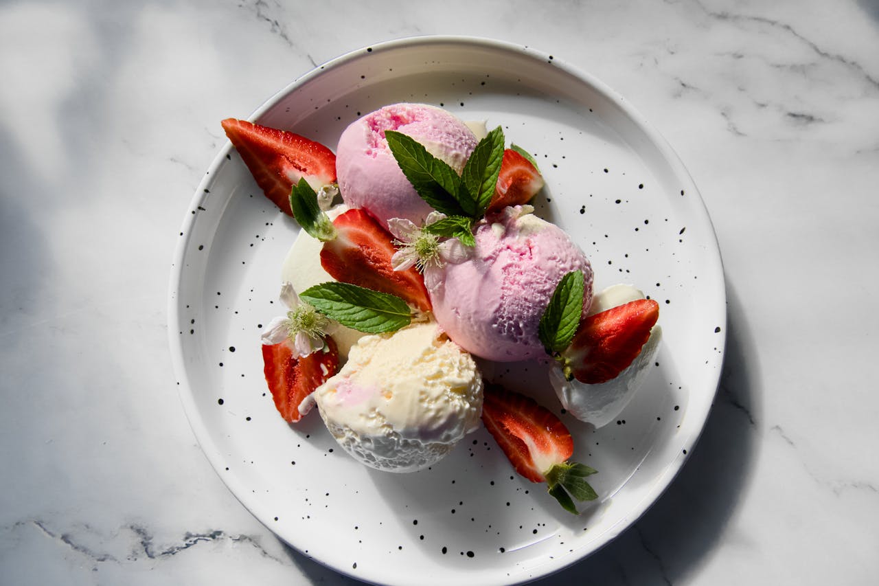 why-choose-us A refreshing plate of strawberry and vanilla ice cream with fresh mint and sliced strawberries.