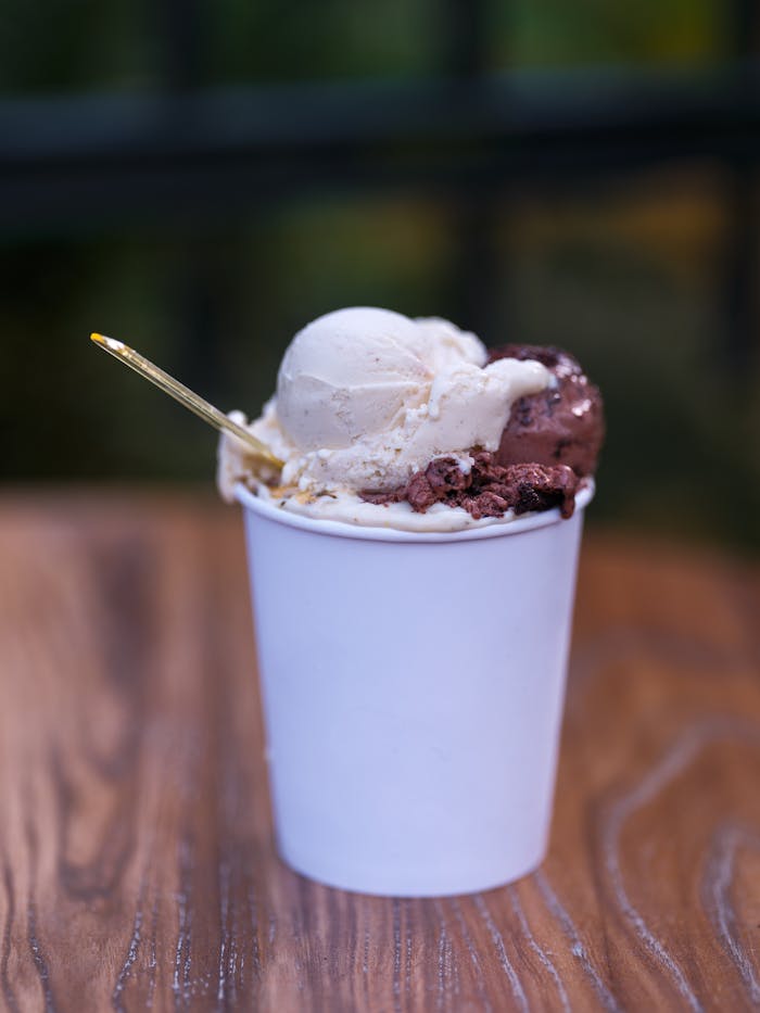 Indulge in a double scoop of creamy ice cream with chocolate and vanilla flavors, served in a cup.