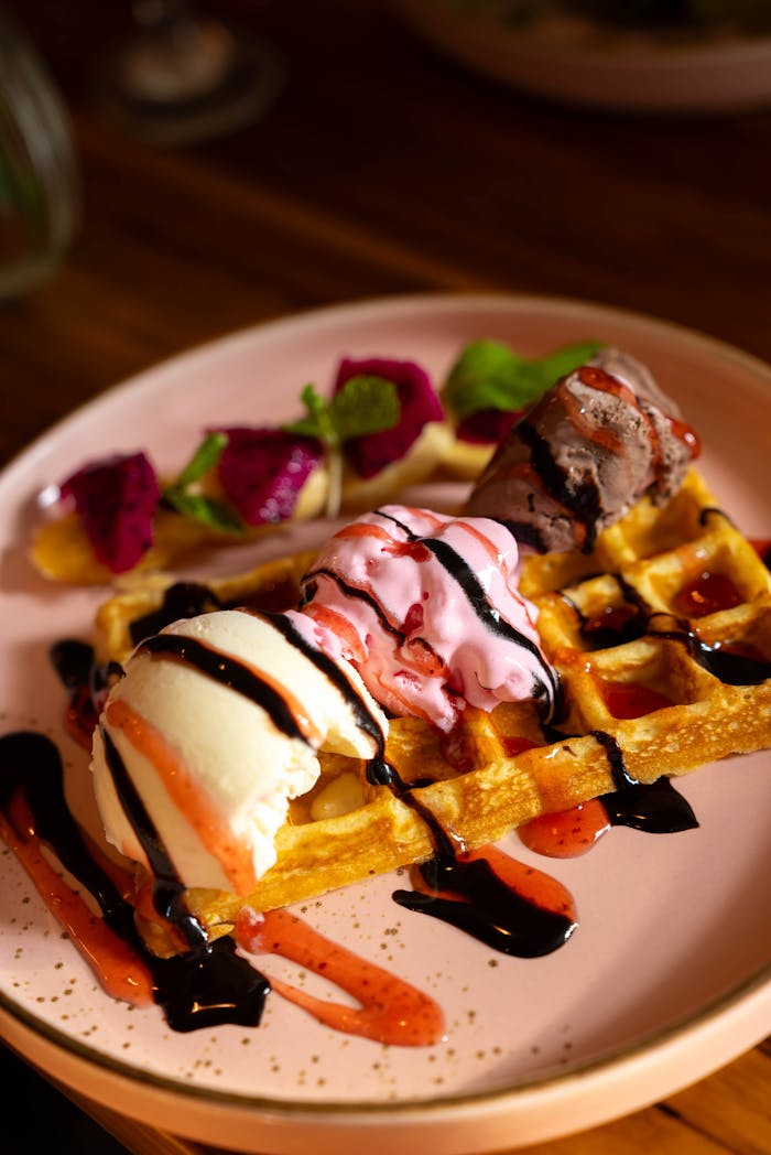 Delicious dessert of waffles topped with assorted ice cream scoops and fresh fruits.