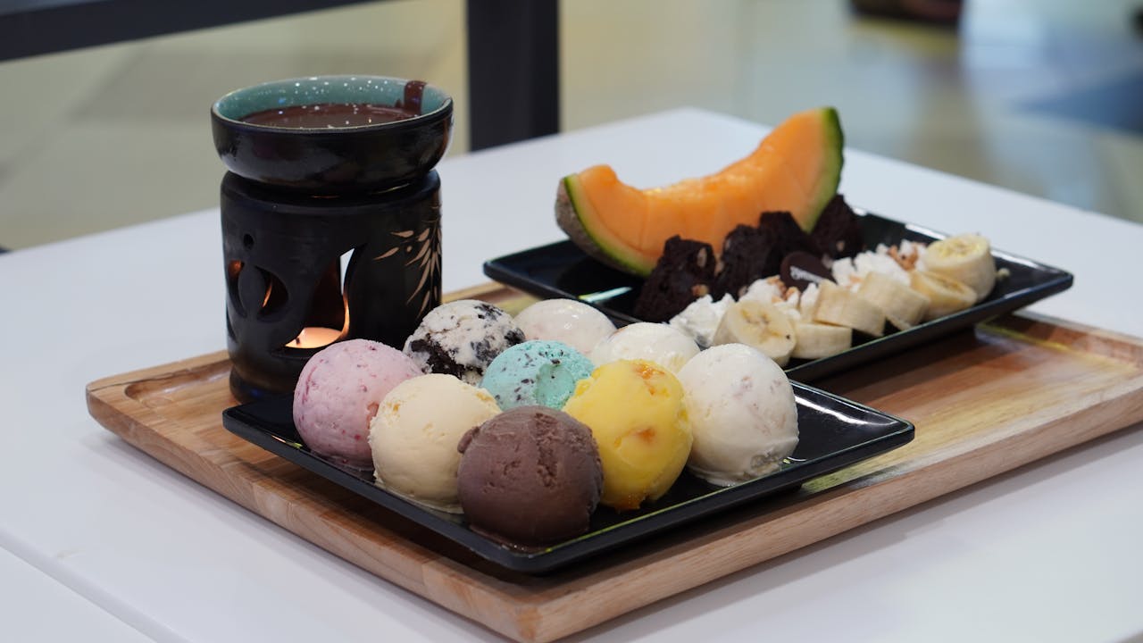 about-01 A vibrant dessert platter featuring assorted ice cream, fruits, and hot chocolate for a delightful treat.