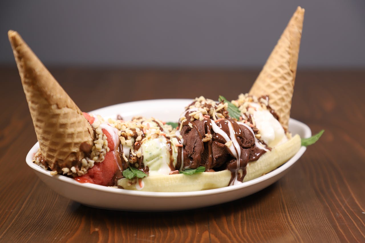 hero-img Savory banana split topped with ice cream cones and chocolate drizzle in a white bowl.