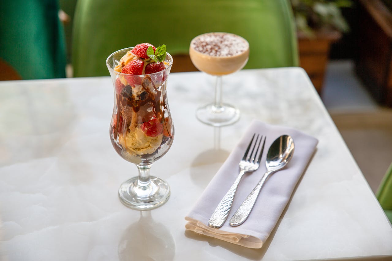 A delicious ice cream sundae with strawberries and a creamy dessert on a white table.