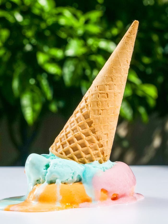 Close-up of a melting ice cream cone with vibrant colors on a sunny day.