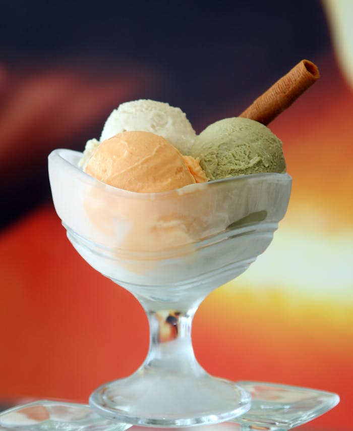 Indulge in a trio of creamy ice cream scoops in a stylish glass dish, perfect for dessert lovers.